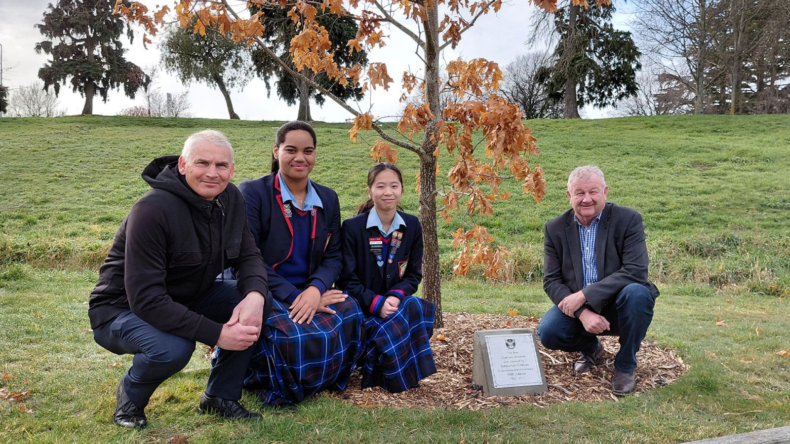 Two students and two adults near tree banner image