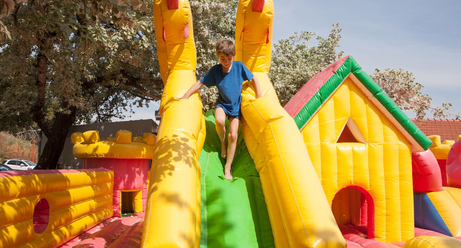 A boy is playing on a bouncy castle banner image