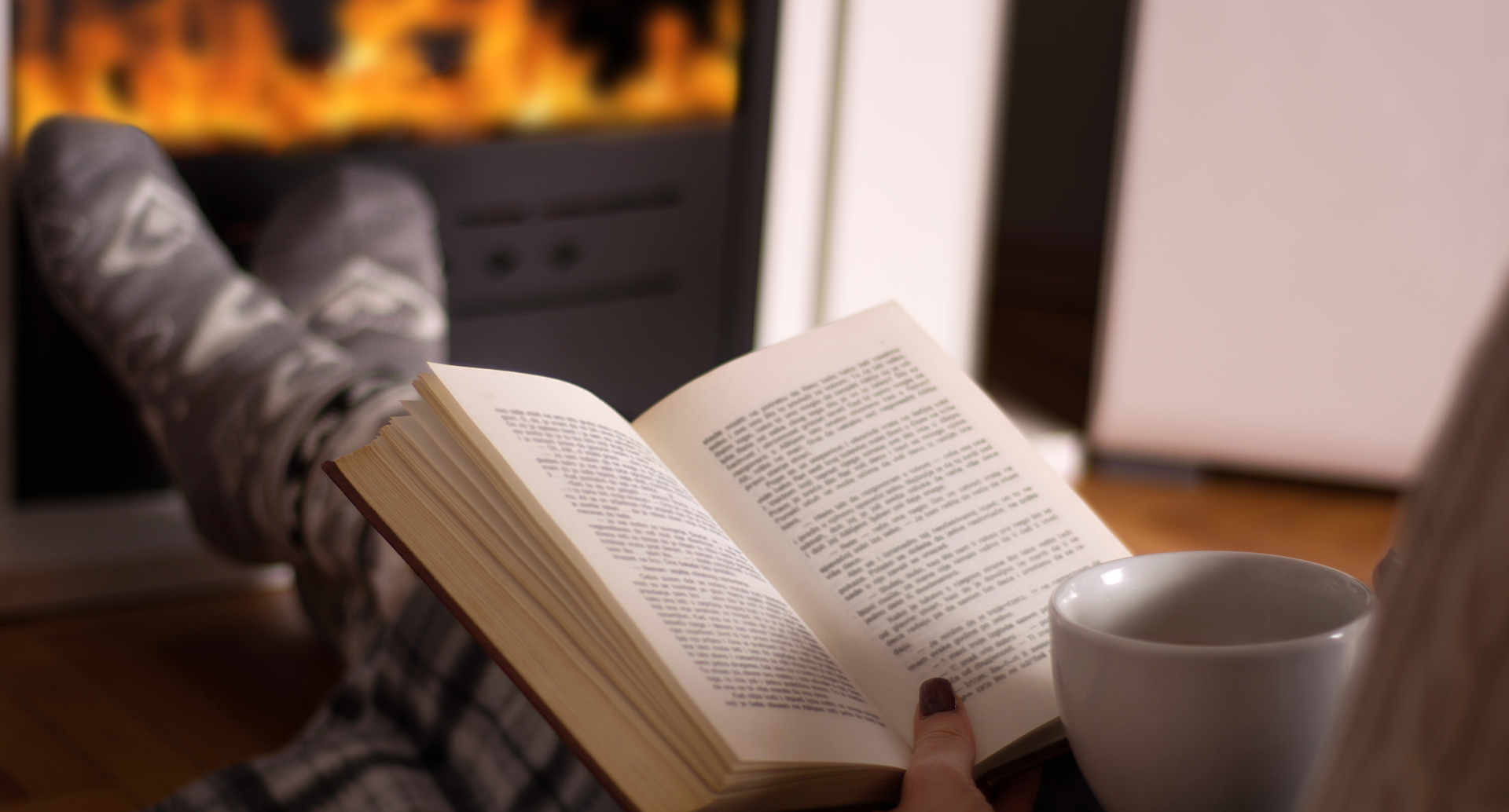 person reading a book by a fire
